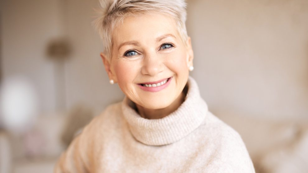 szép idős nő garbóban pasztel színek mosolyog