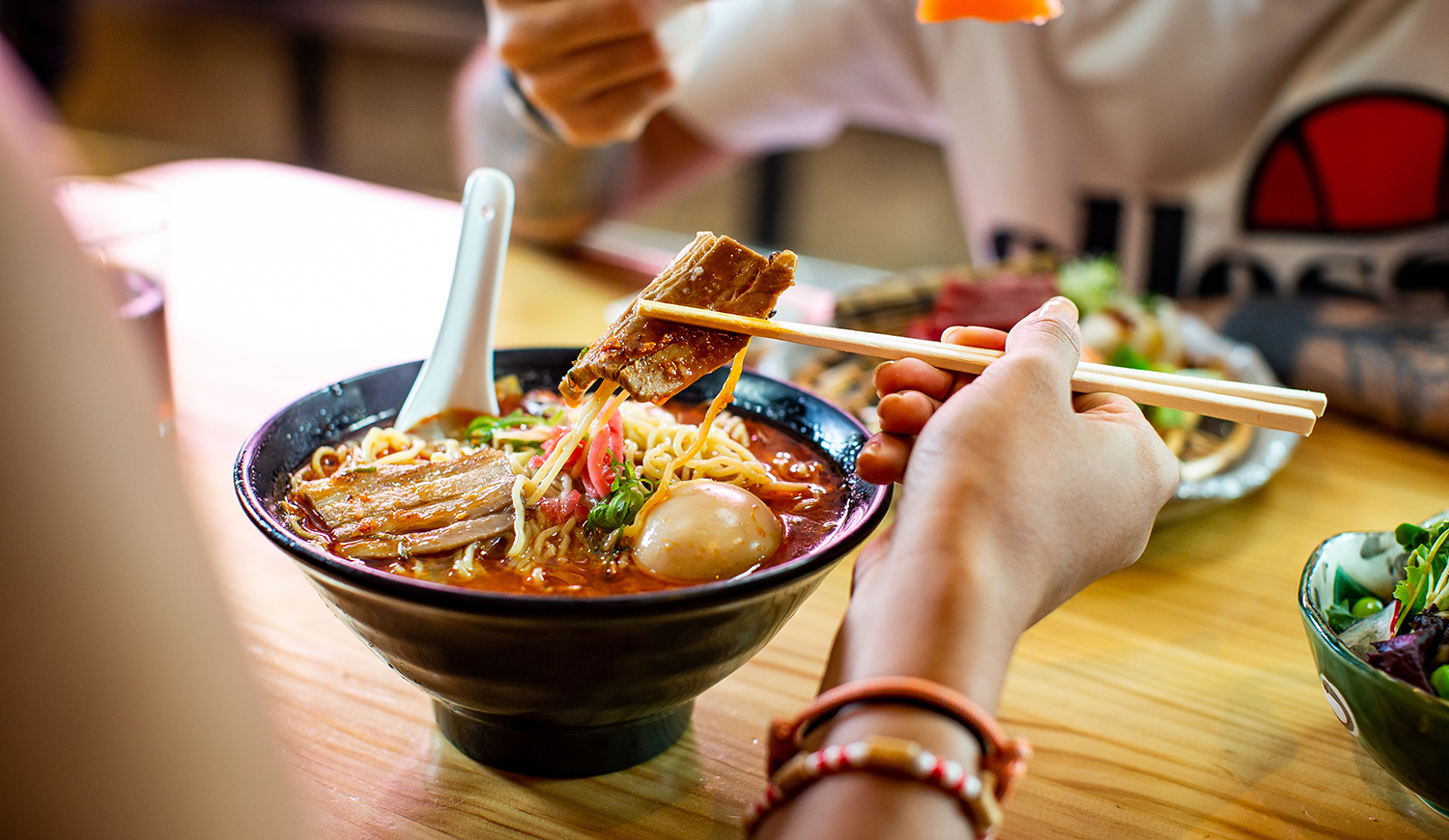 Ráment pálcikával evő nő