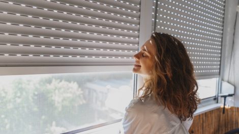 redőny előtt áll egy nő mosolyog