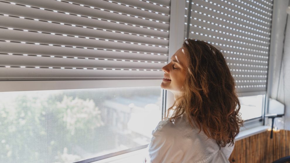 redőny előtt áll egy nő mosolyog