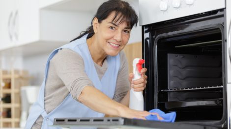 szódabikarbónával sütőt takarít egy középkorú nő