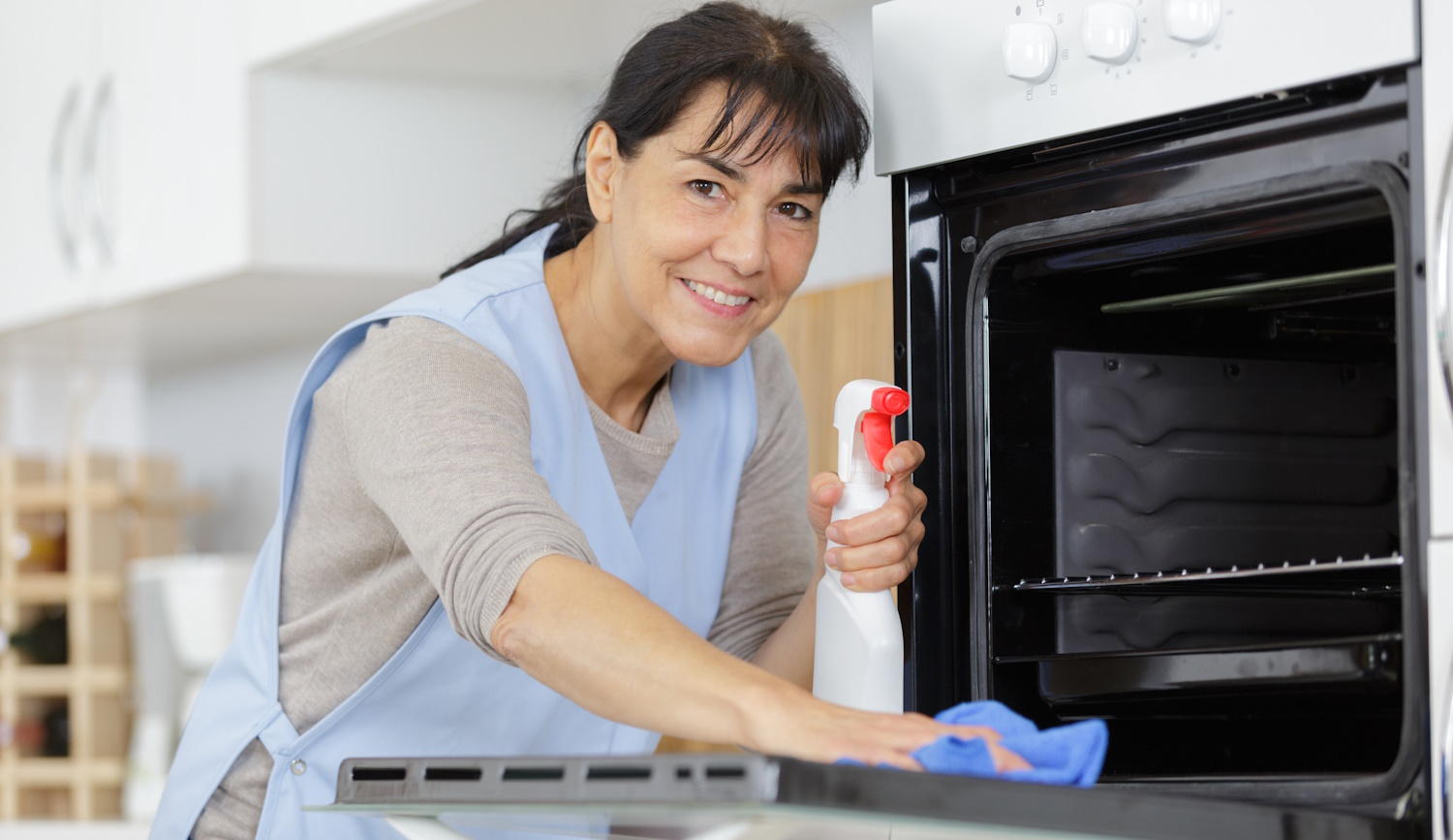 szódabikarbónával sütőt takarít egy középkorú nő