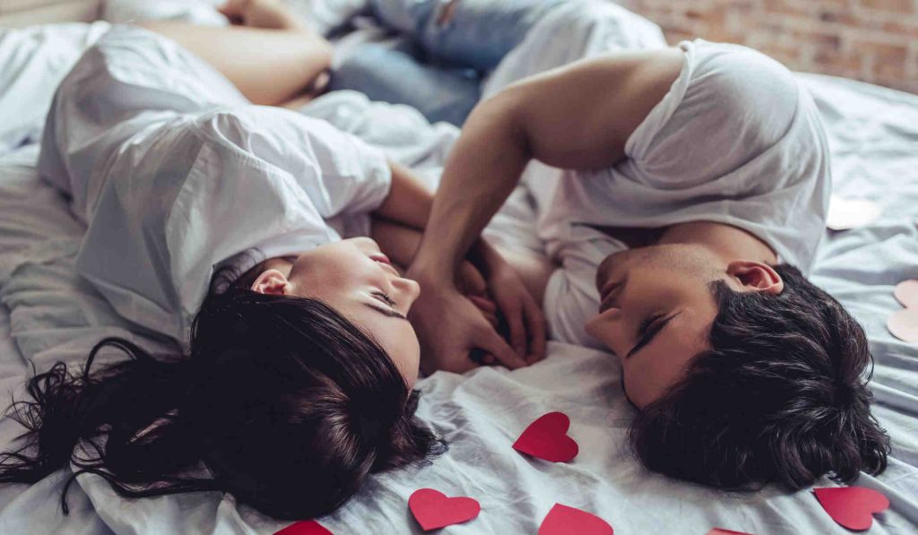 szerelmes pár fekszik az ágyon szívek között