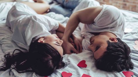 szerelmes pár fekszik az ágyon szívek között