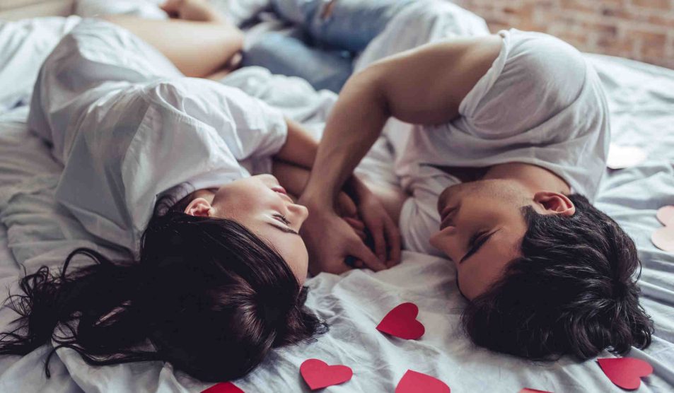 szerelmes pár fekszik az ágyon szívek között