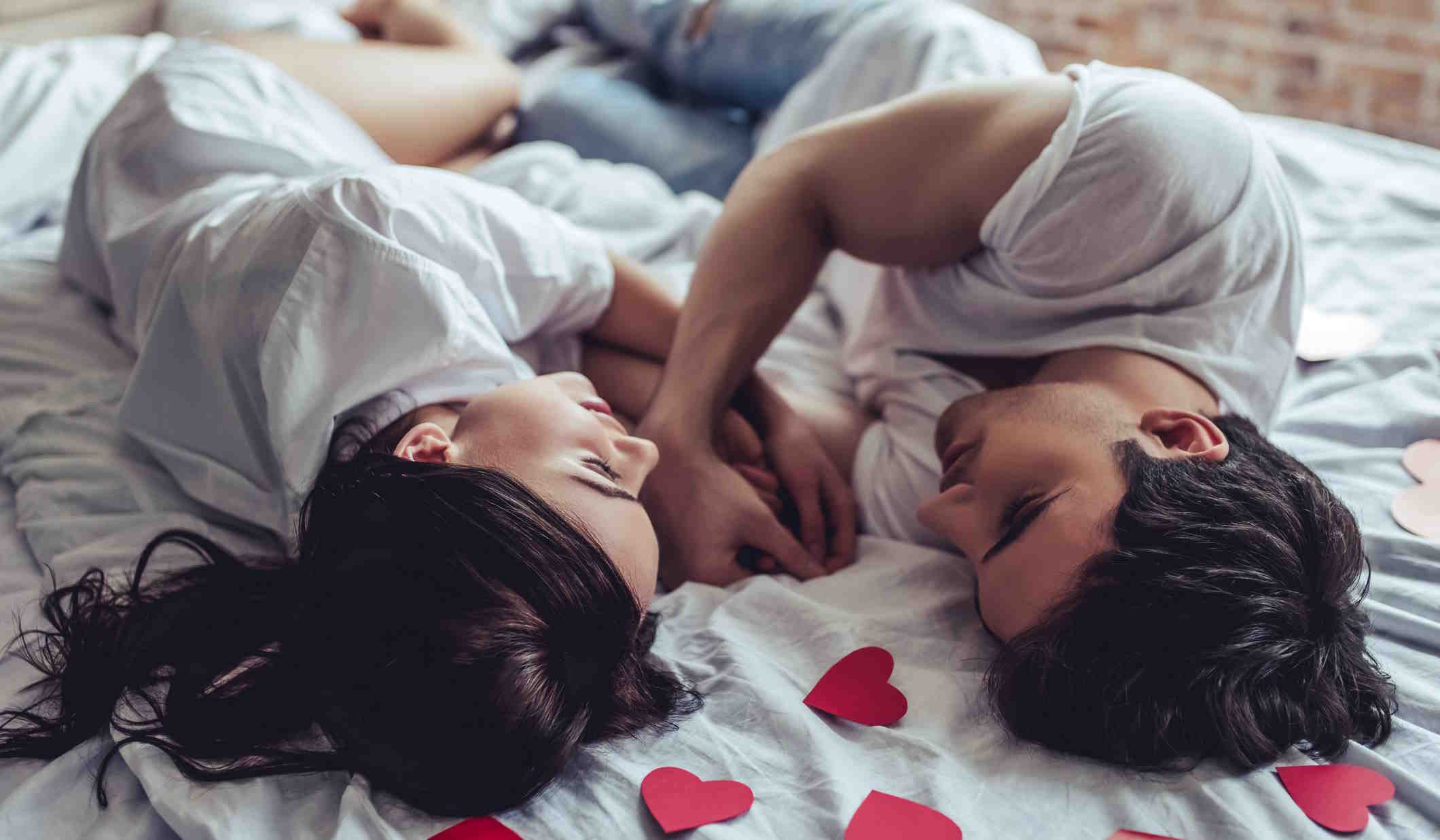 szerelmes pár fekszik az ágyon szívek között