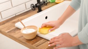 mosdókagylót tisztít egy nő szódabikarbónával és szivaccsal