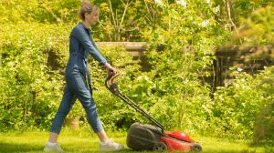 tavasszal füvet nyír a akertben egy csinos nő