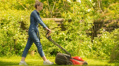 tavasszal füvet nyír a akertben egy csinos nő