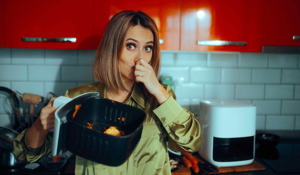 Büdös airfryer, nő befogja az orrát