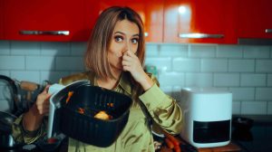 Büdös airfryer, nő befogja az orrát