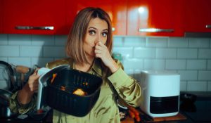Büdös airfryer, nő befogja az orrát