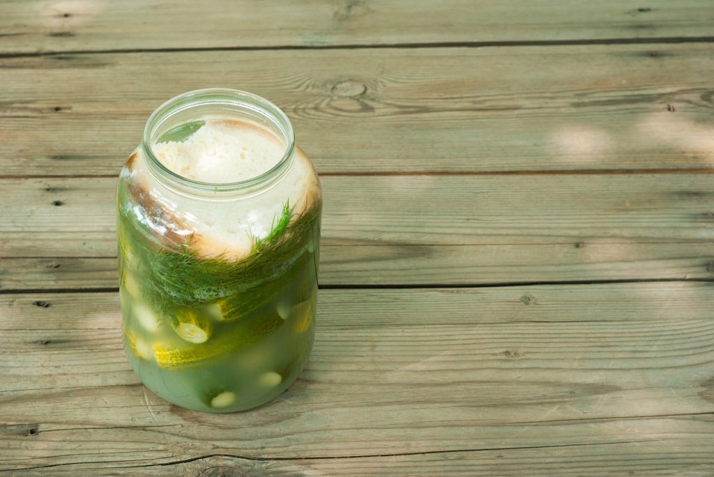 pickled cucumbers in glass jar on wooden table | Meglepetés Kovászos uborka üvegben