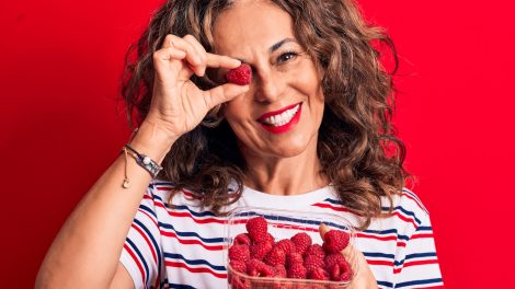 málnaszemet tart a szeme elé egy 60+-os nő viccesen