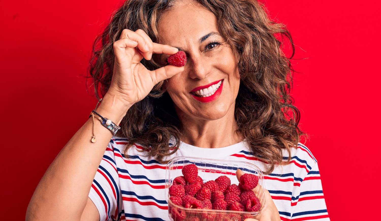 málnaszemet tart a szeme elé egy 60+-os nő viccesen