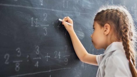 Kislány matematikai egyenleteket old meg a táblán