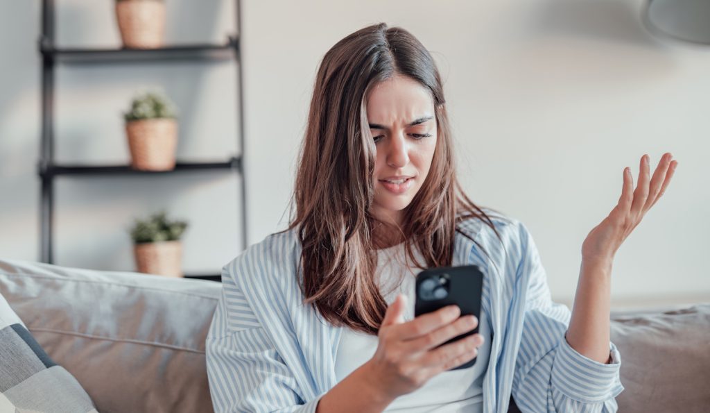 fiatal barna nő mérges a mobiltelefonjára