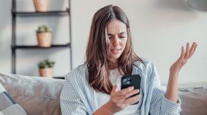 fiatal barna nő mérges a mobiltelefonjára