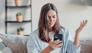 fiatal barna nő mérges a mobiltelefonjára