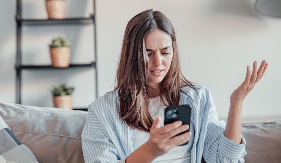 fiatal barna nő mérges a mobiltelefonjára