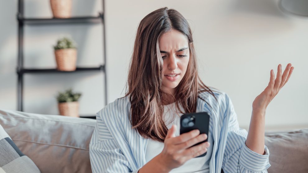 fiatal barna nő mérges a mobiltelefonjára