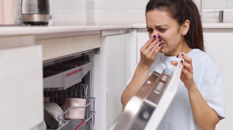 Egy lány undorodik a mosogatógép szagától