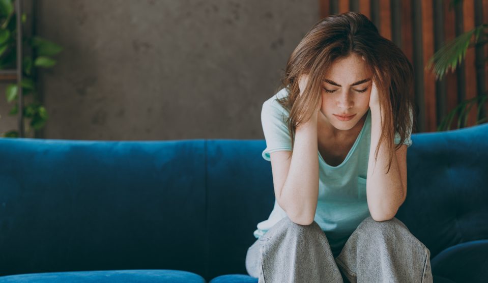 Nő ül a kanapén és stresszel