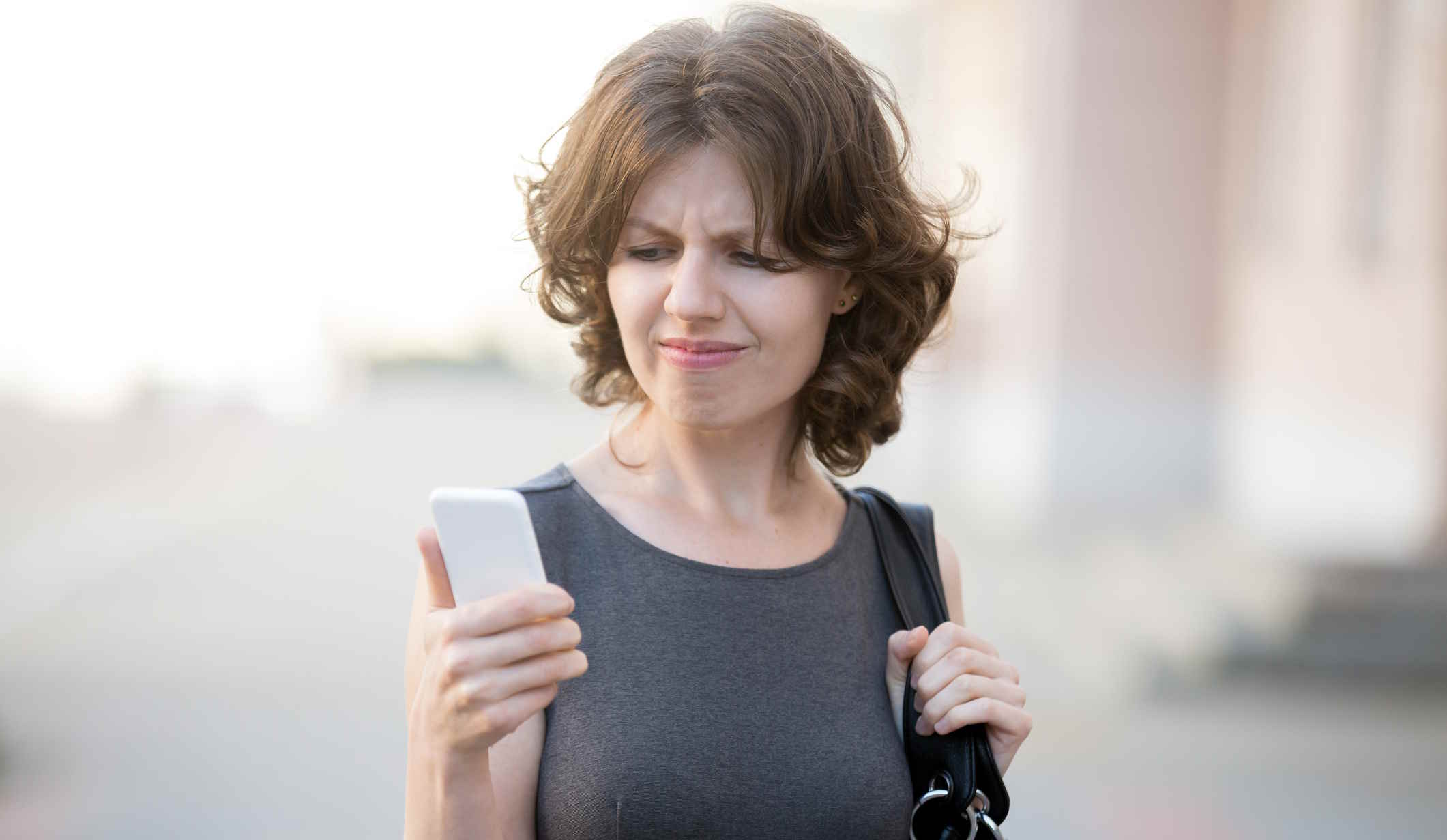Nő az utcán sétálva nézi a telefonját