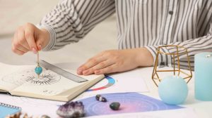 Asztrológus zodiákus kereket és ingát használ a sors előrejelzéséhez az asztalnál