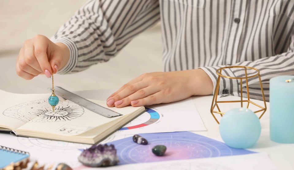 Asztrológus zodiákus kereket és ingát használ a sors előrejelzéséhez az asztalnál | Meglepetés Asztrológus zodiákus kereket és ingát használ a sors előrejelzéséhez az asztalnál