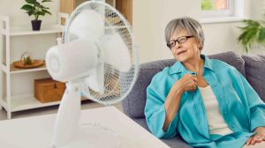 Idősebb hölgy ül a ventilátor előtt