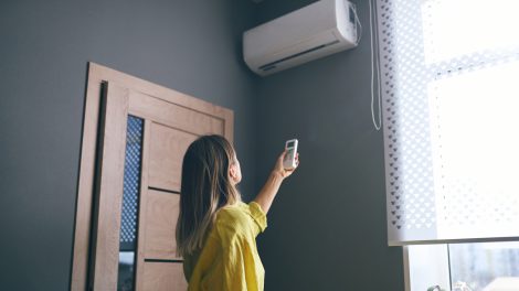 nő bekapcsolja a légkondit a nappaliban
