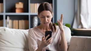 aggódó nő a kanapén a telefonját nézi