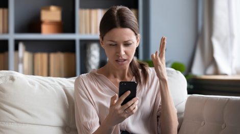 aggódó nő a kanapén a telefonját nézi