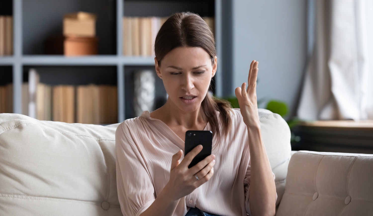 aggódó nő a kanapén a telefonját nézi