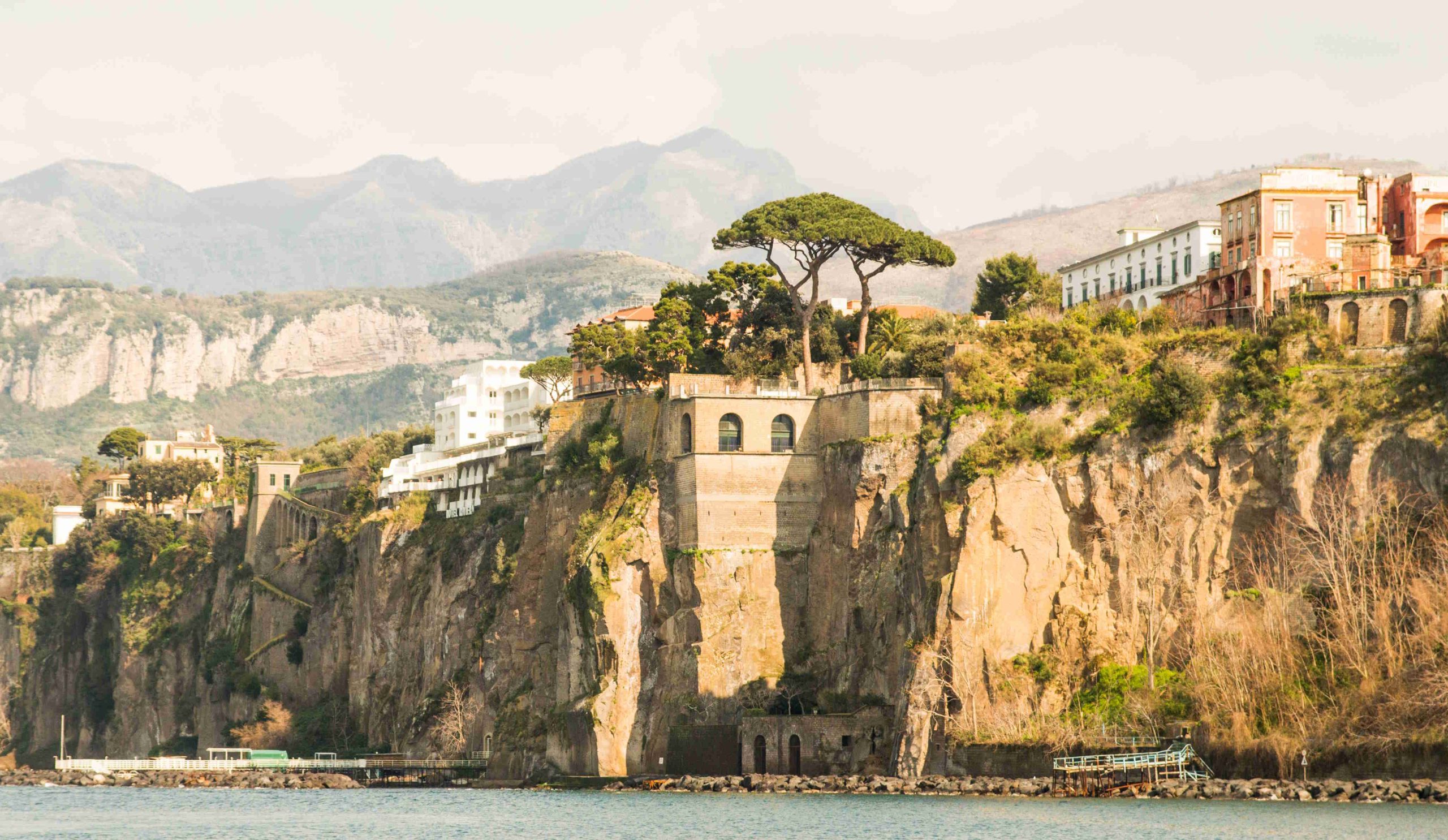 Egy napsütötte szikla Sorrento felett, tetején fákkal és házakkal