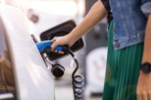 nő elektromos autót tölt