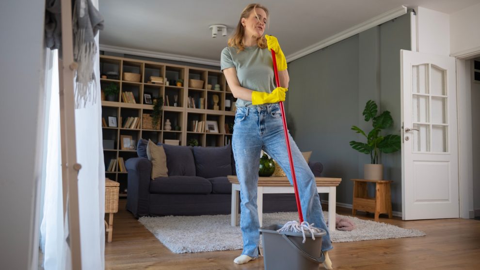 nő fahéjas vízzel felmos a nappaliban és boldog