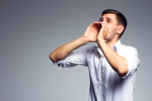 hangosan beszélő férfi tölcsért csinál a kezéből