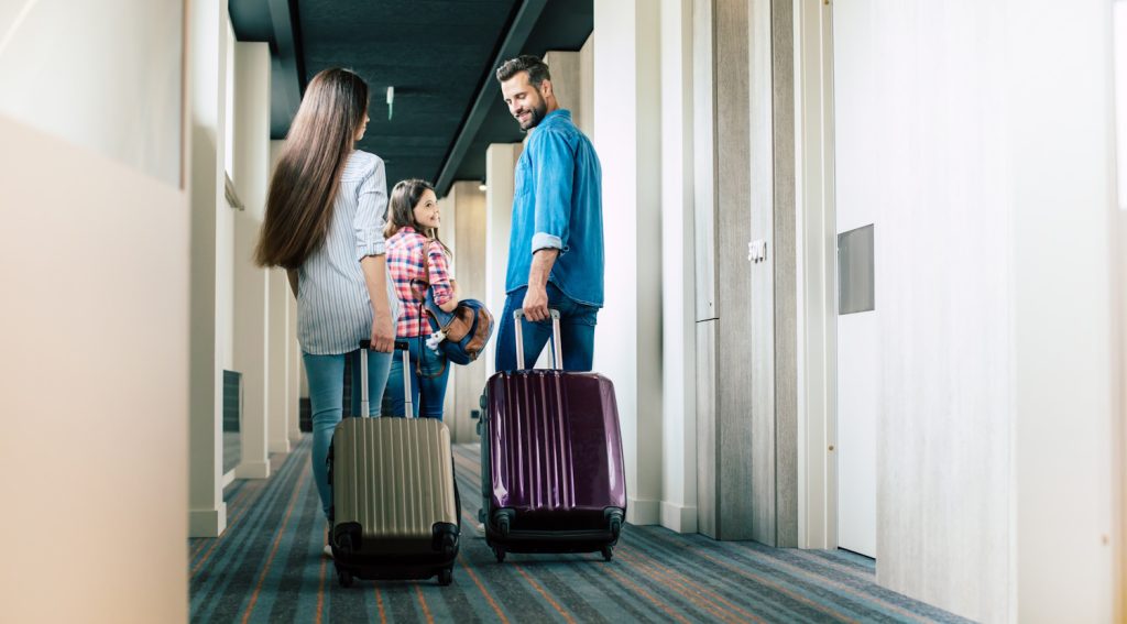 szálloda folyosólyán húzza a bőröndjeit egy család