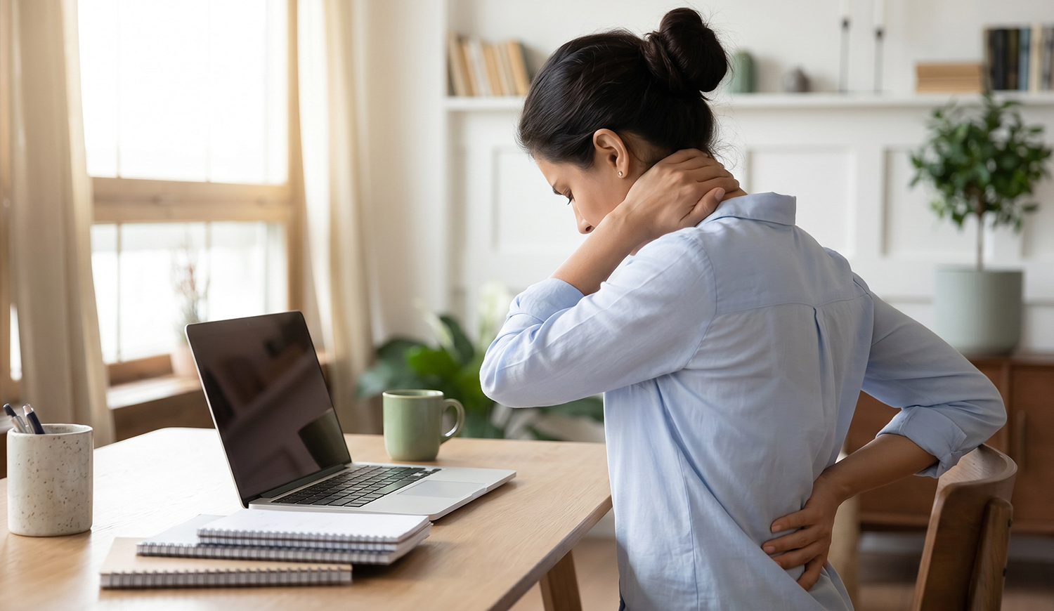 Stresszes fiatal nő otthon dolgozik, nyaki fájdalma van.
