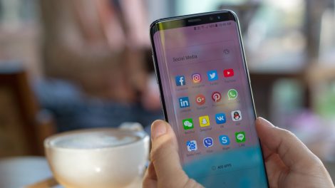 samsung mobiltelefont tart a kezében egy nő egy kávézóban