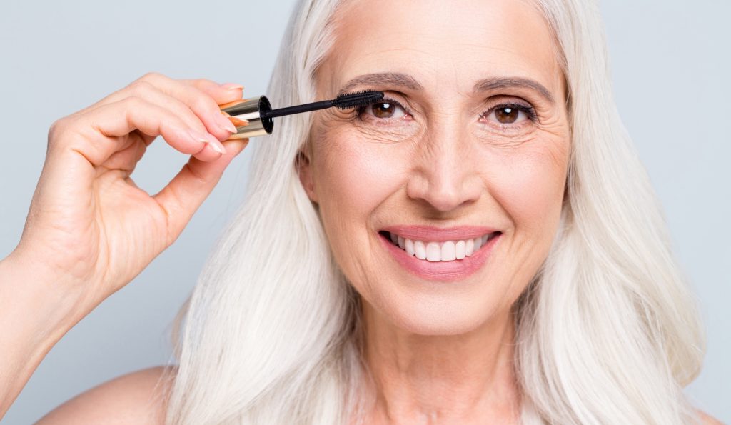 szempilláját festi egy szép ősz hajú nő