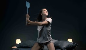 Nő idegesen próbálja éjszaka lecsapni a szúnyogot
