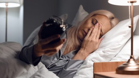 stresszes 60-as nő felébred az éjszaka közepén és az órájára néz