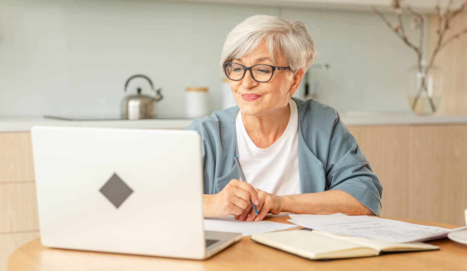 Idős nő ül a laptop előtt és mosolyog