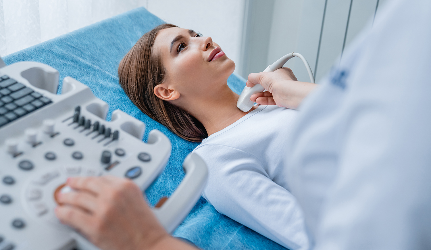 Egy nő nyakát ultrahangos készülékkel vizsgálja meg egy doktornő