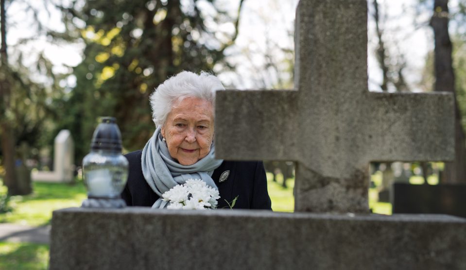 Elderly widow bringing chrysanthemums flowers to a grave | Meglepetés özvegy nő krizantémot visz a sírra a temetőbe, a kép a 2026-os halottak nai mindenszenteki krizantém árakat illusztrálja